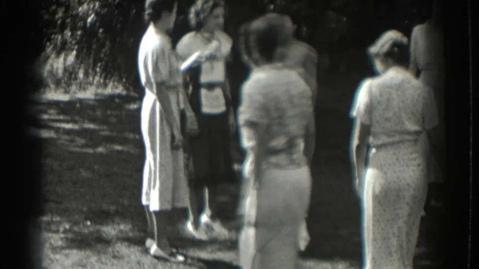 Women gather outdoors in Southampton, New York, in 1937 8mm home-movie footage, with trees and a shaded path behind them.