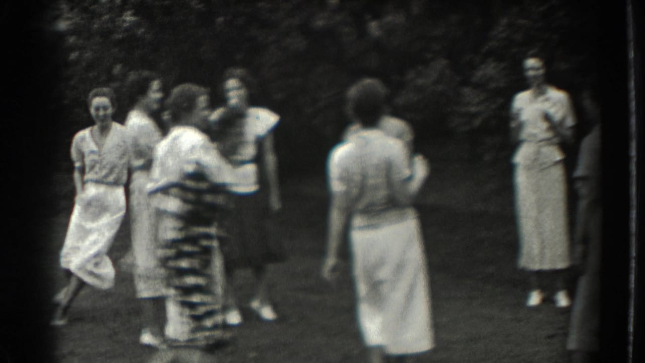 Adult women in dresses gather and move on a grassy lawn.
