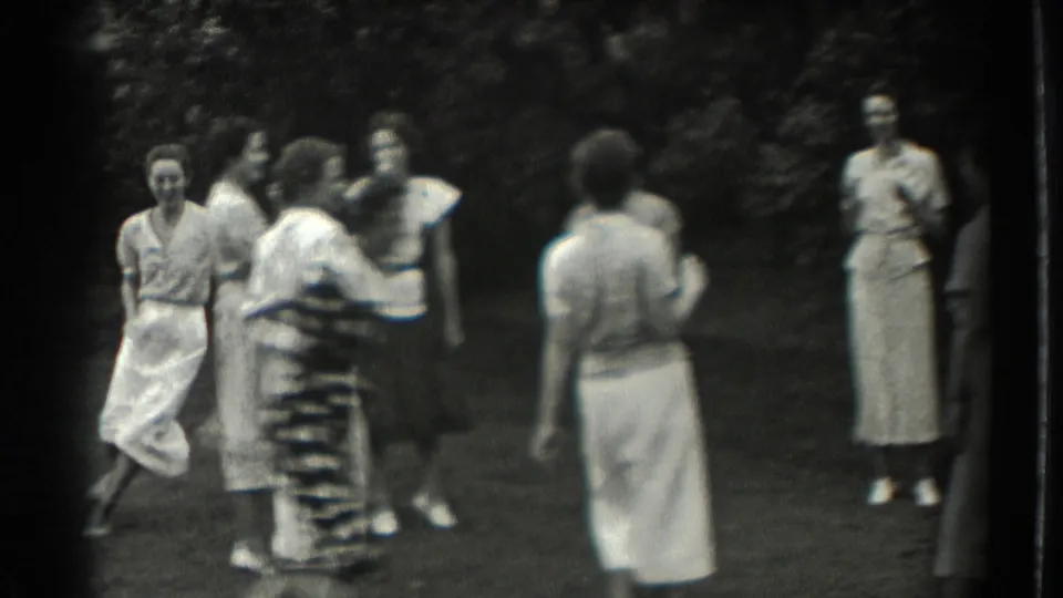 In 1937 Southampton home-movie footage, adult women in summer dresses stand and move during a lawn game.