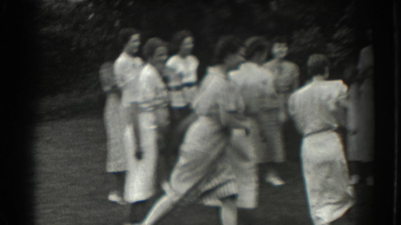 A woman moves quickly across a lawn while others watch nearby.