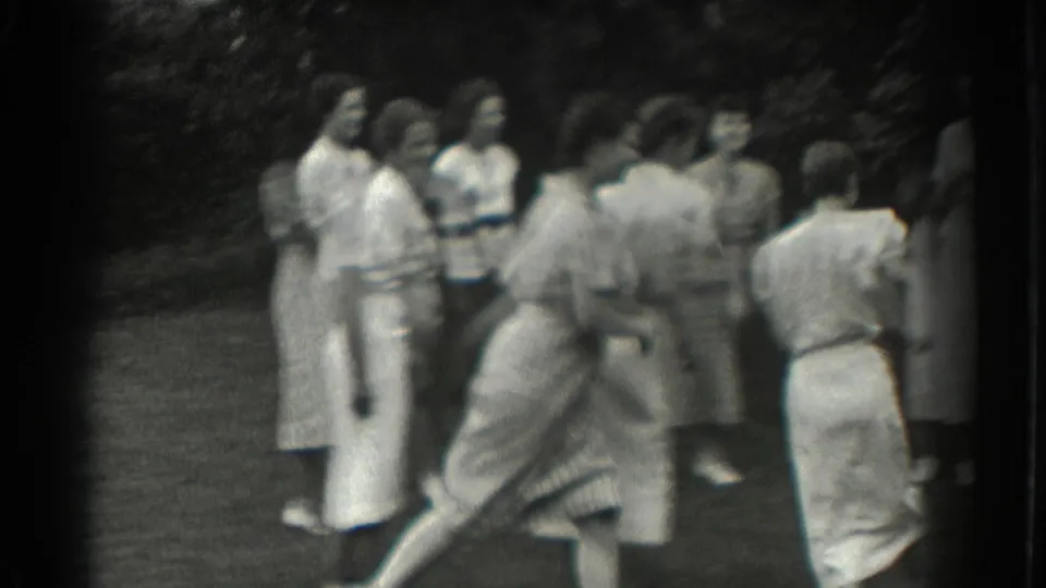 In Southampton home-movie footage, a woman runs playfully past a group of women gathered on the grass.