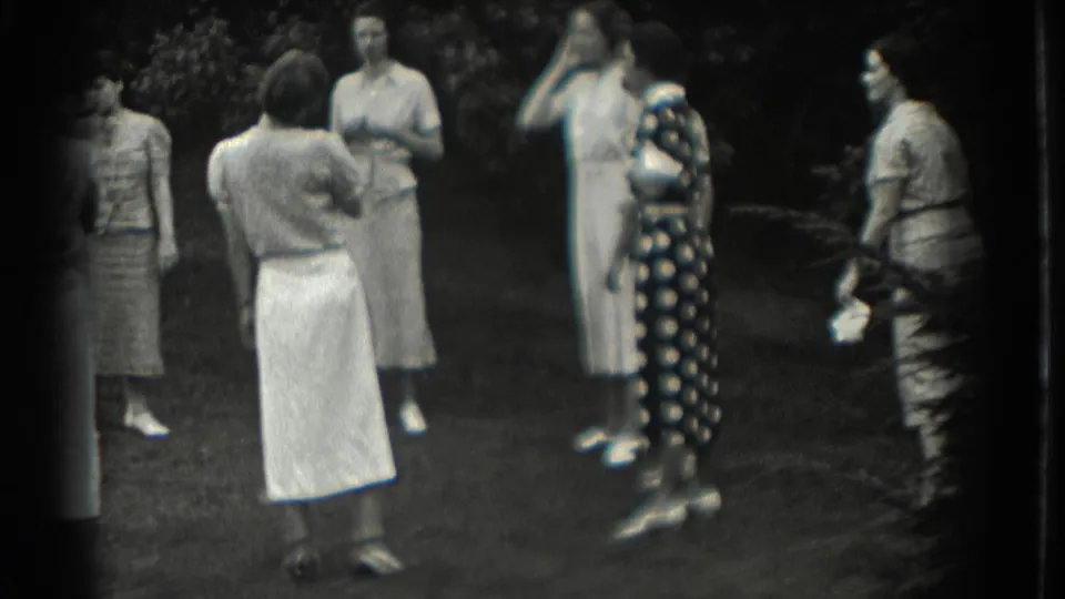 A group of women stands outdoors in Southampton, with a dark polka-dot dress prominent among light skirts and dresses.