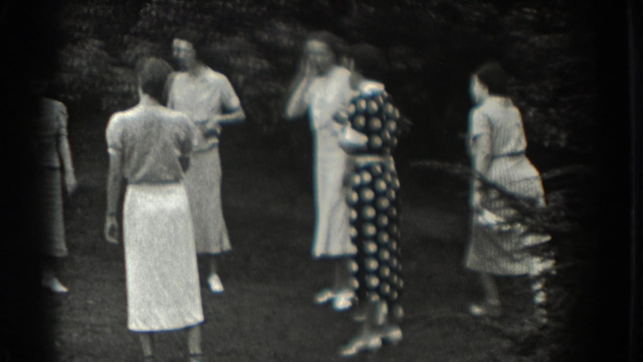 Women in light dresses stand in a loose circle on grass near trees.