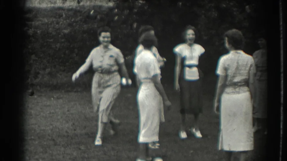 A woman steps across the lawn as other women watch during a 1937 Southampton home-movie game scene.