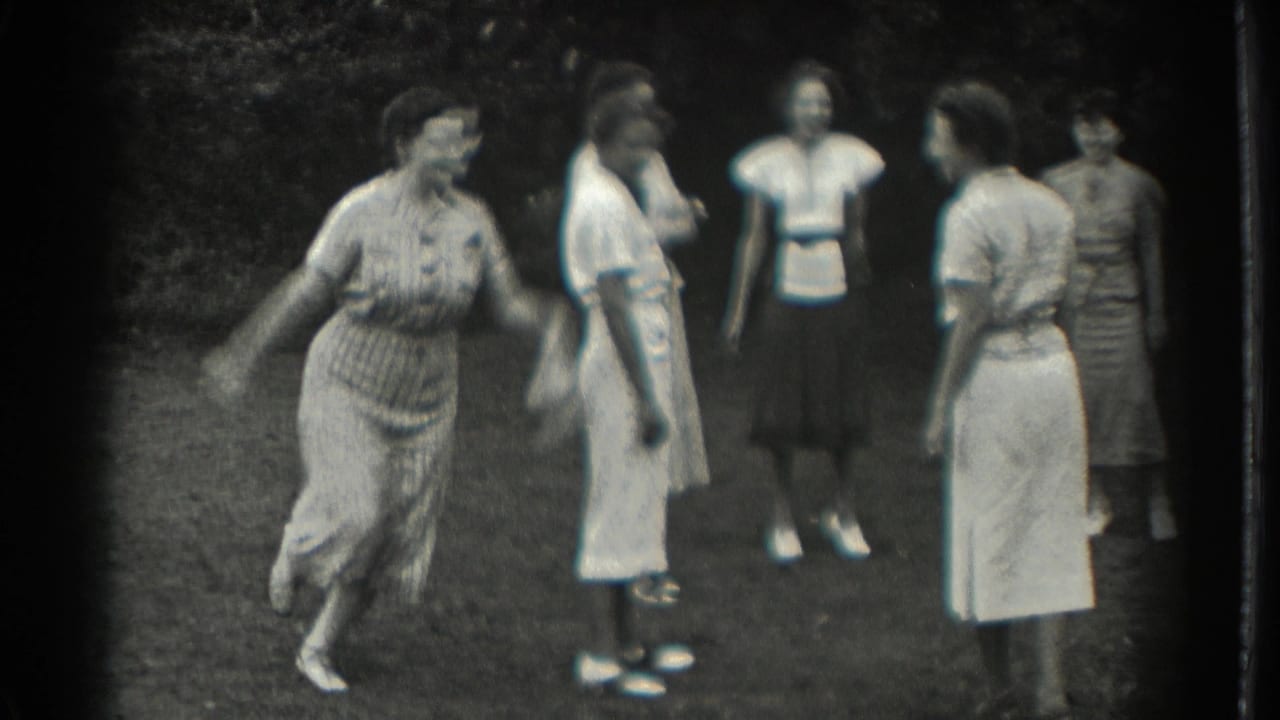 Women standing on grass while one woman moves as if throwing or catching an object.