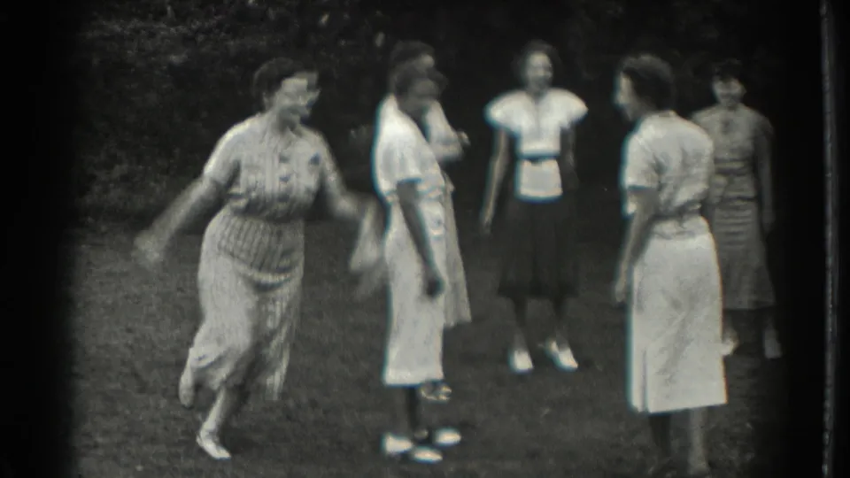 Adult women in 1937 Southampton, New York, stand in a garden while one woman appears to play a casual throwing game.