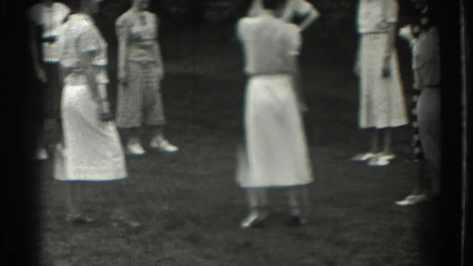 Several adult women in dresses stand on a Southampton lawn, likely between moments of an informal outdoor game.