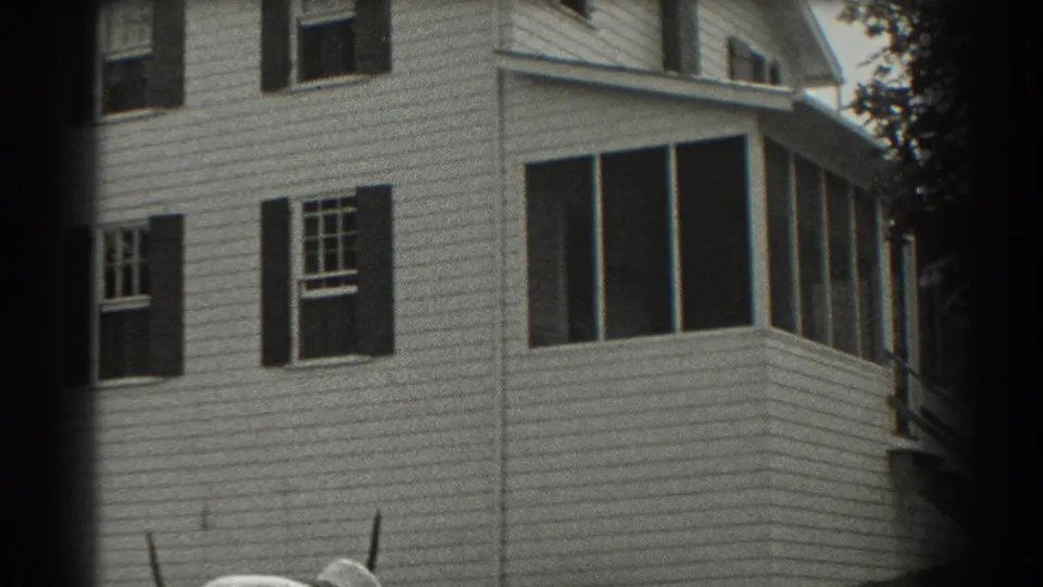1937 Southampton home-movie frame showing a white clapboard house with dark shutters, multi-pane windows, and a screened porch.