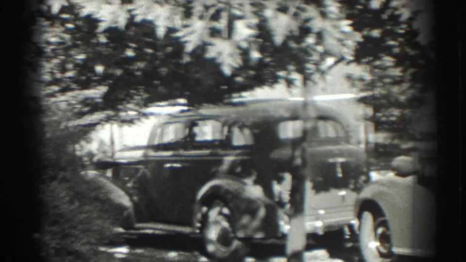 In 1937 Southampton, New York, two young women appear near parked classic automobiles on a sunlit tree-lined street.