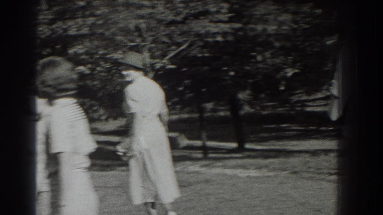 Two women in period dresses and hats walk through a leafy Southampton park in 1937 home-movie footage.
