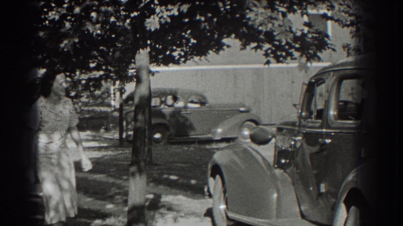Woman in a light dress stands near a tree as 1930s cars line a shaded street.