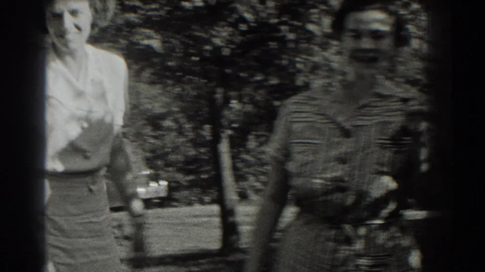 Two women in period clothing walk toward the camera in a leafy Southampton, New York outdoor setting, 1937 metadata supplied.