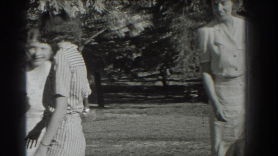 Three women are visible beneath trees in Southampton, New York, with one figure near the right edge and two partly cropped at left.
