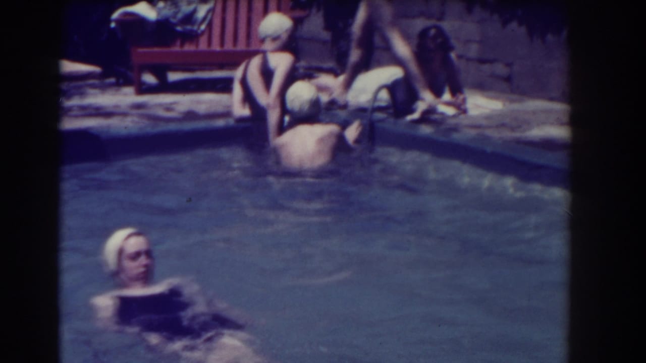 Women in swim caps gather in and around a backyard swimming pool.