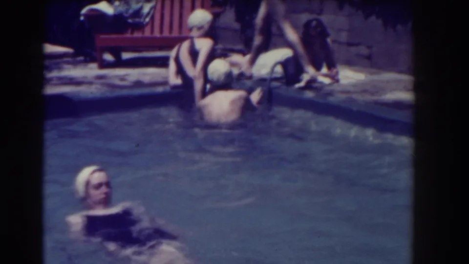 1937 Southampton home-movie frame showing women in one-piece swimsuits and white caps at a pool edge.
