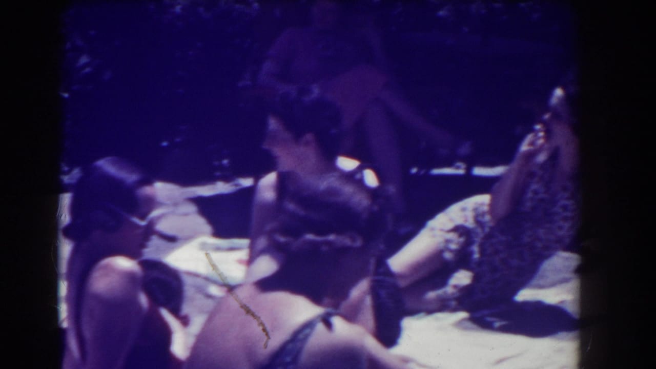 Women in swimsuits lounge on towels outdoors, with one woman turned toward another.