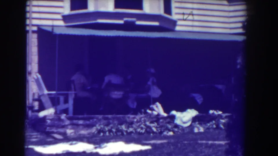 1937 Southampton home-movie frame showing women gathered near a shaded porch and garden outside a house.