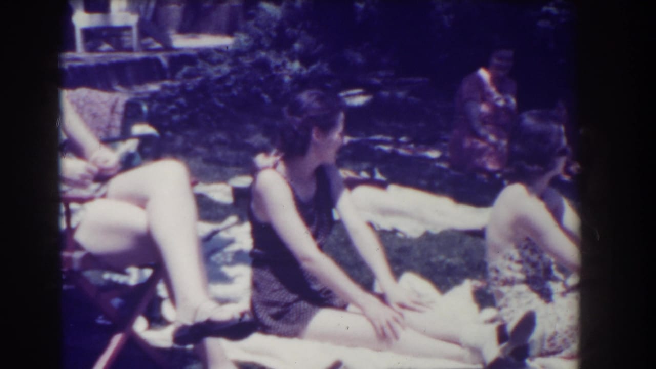 Women in period swimwear lounge on towels in a sunny Southampton garden in 1937 home-movie footage.