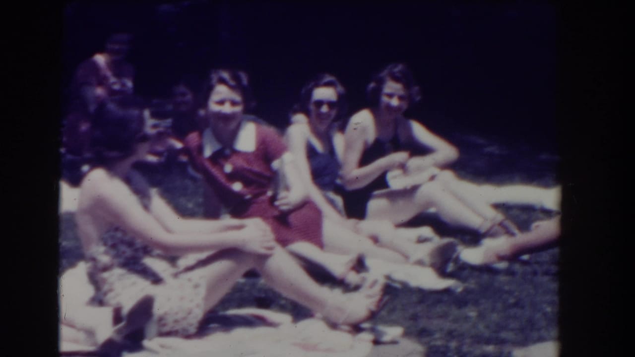 Women seated on towels face the camera in a sunny outdoor setting.