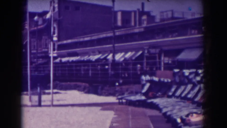 1938 Atlantic City boardwalk shopping view with storefront awnings, benches, poles, melting snow, and a few distant people or figures.