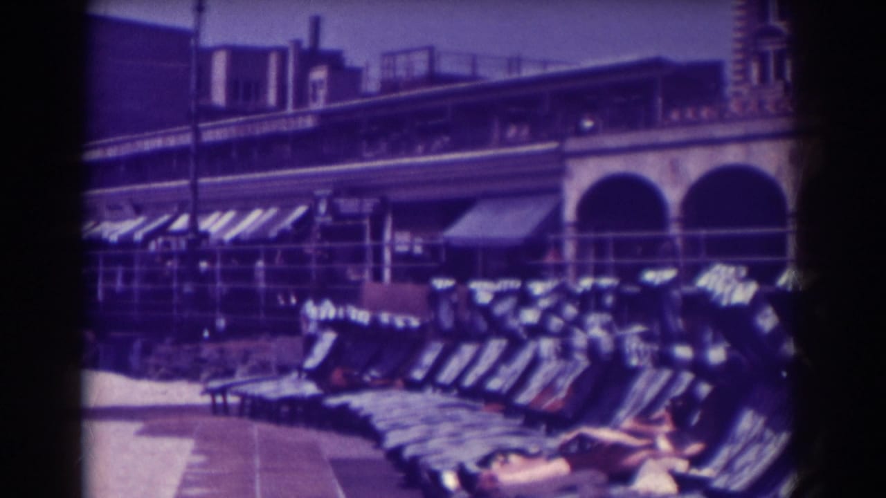 Long row of lounge chairs with boardwalk buildings and awnings behind them.