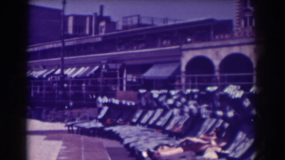 Atlantic City beach chairs stretch across the frame with arched colonnades and striped awnings in the background.