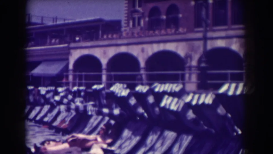 1938 Atlantic City beach scene with a woman reclining in the foreground, empty chairs receding, and arched boardwalk buildings behind.