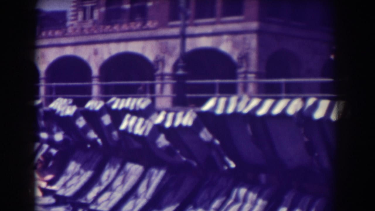 Empty lounge chairs and striped awnings with arched openings in the background.