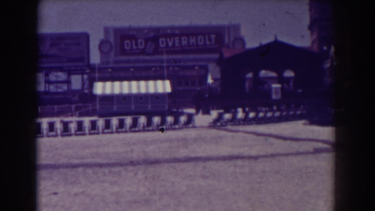 Training sleds lined along a sandy field with an Old Overholt billboard behind them.