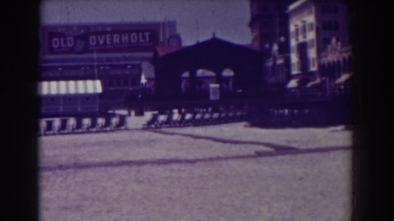 Sandy field and training sleds with a billboard, awning, and dark structure in the background.