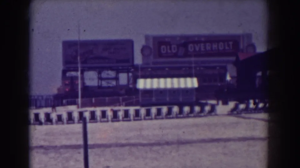 Atlantic City 1938 frame with a sandy field, lined training sleds, railings, and a prominent Old Overholt billboard in the background.