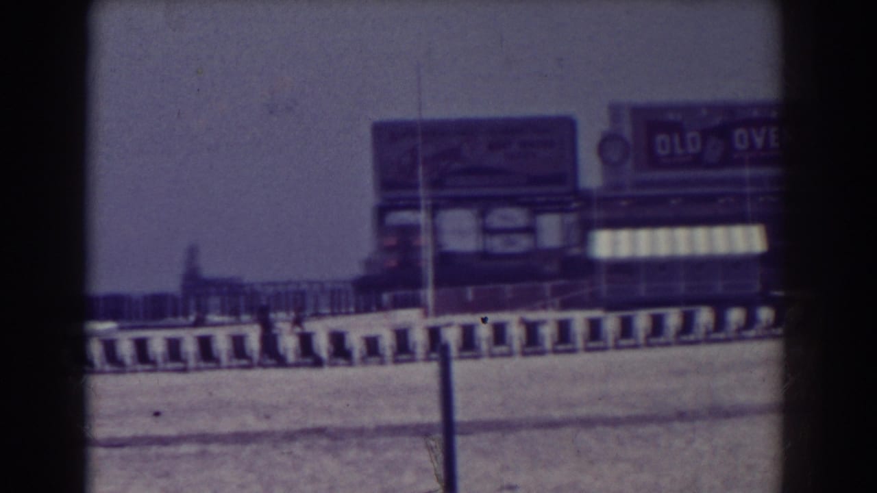 Boardwalk storefront signage and striped awning beside railings near the shore.
