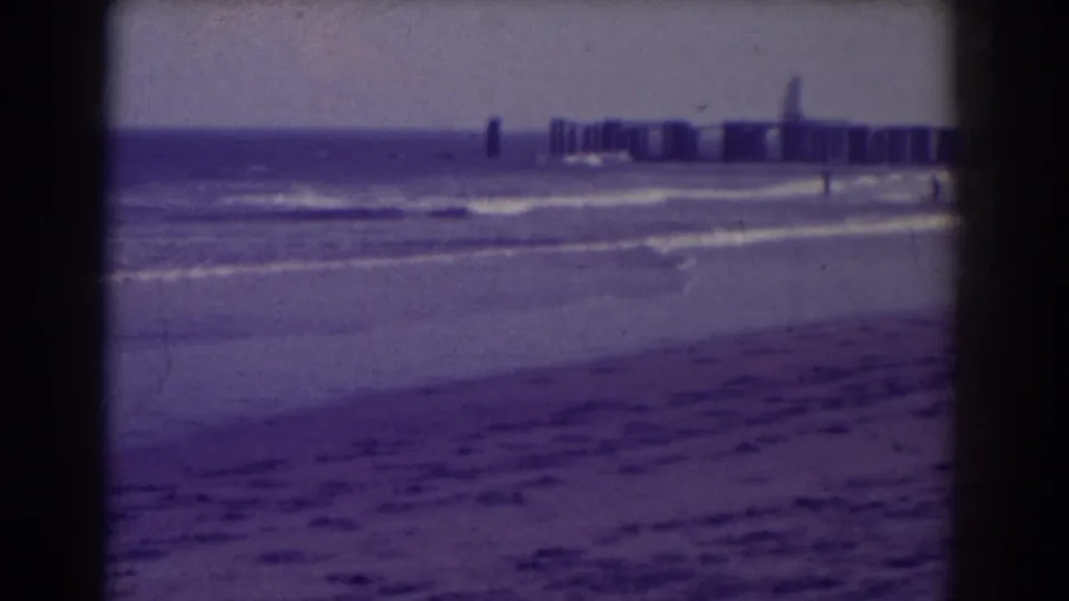 Atlantic City beach scene from 1938 with small surf lines, open sand, and a distant pier under a hazy sky.