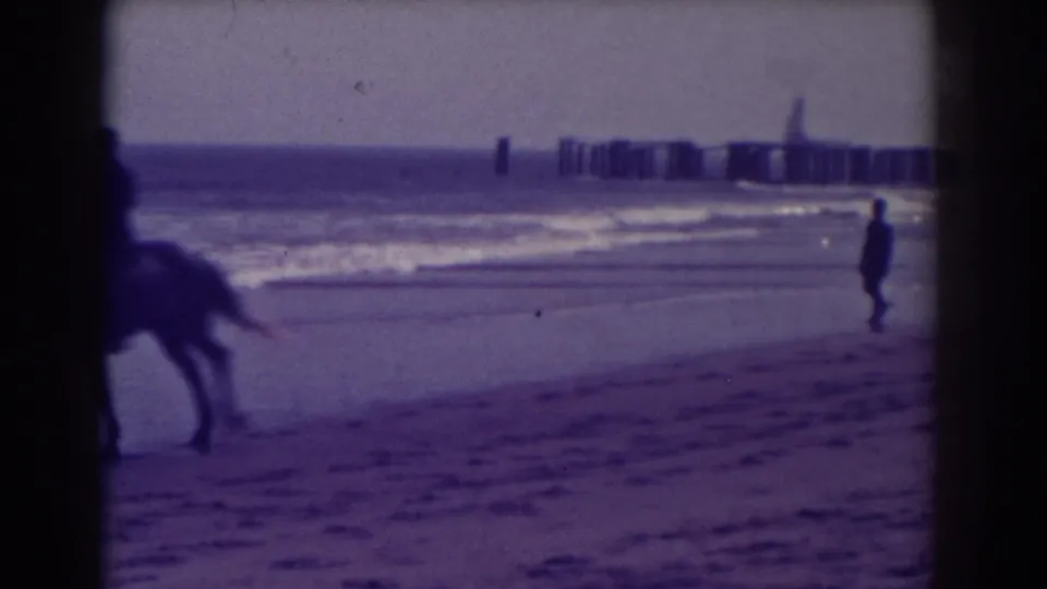 On the Atlantic City shoreline, the rider exits the frame as a lone beachgoer walks beside the waves.