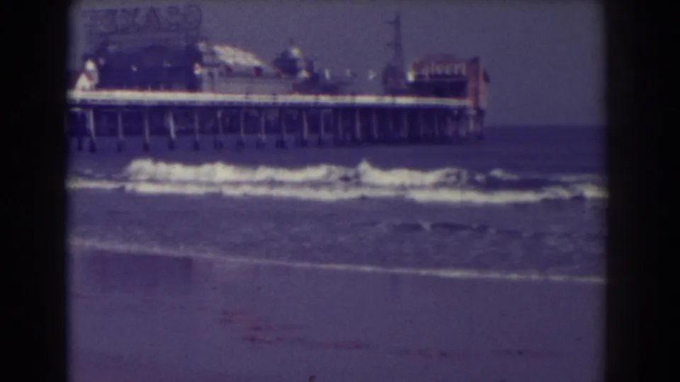 1938 Atlantic City shore view showing waves, wet sand, a long pier, and visible Texaco signage in grainy 8mm footage.
