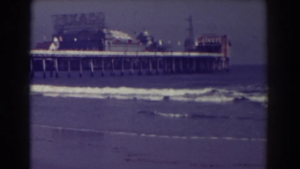 1938 Atlantic City seaside frame with the pier extending across the surf and commercial signage visible above it.
