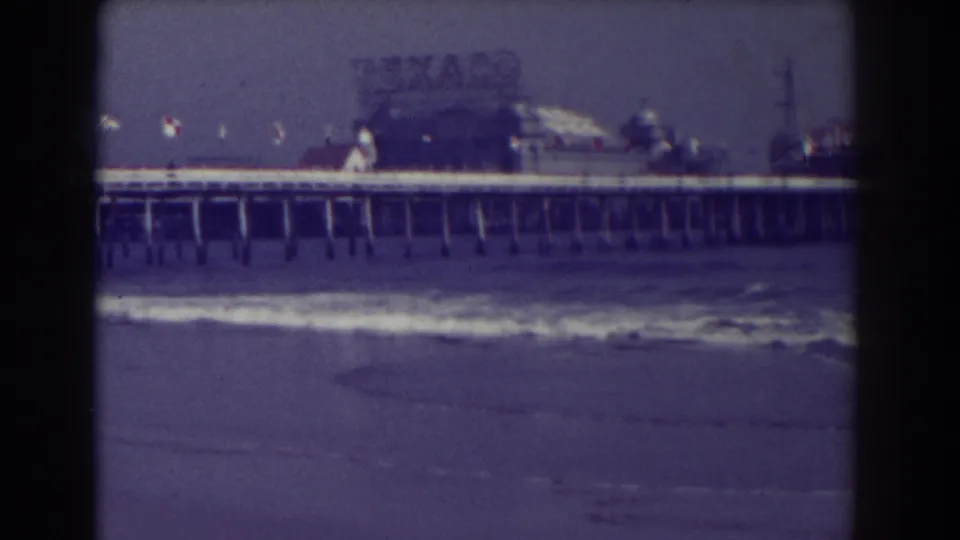 Final 1938 Atlantic City beach frame with ocean waves, pier pilings, rooftop signage, and a visible Texaco sign at the pier end.