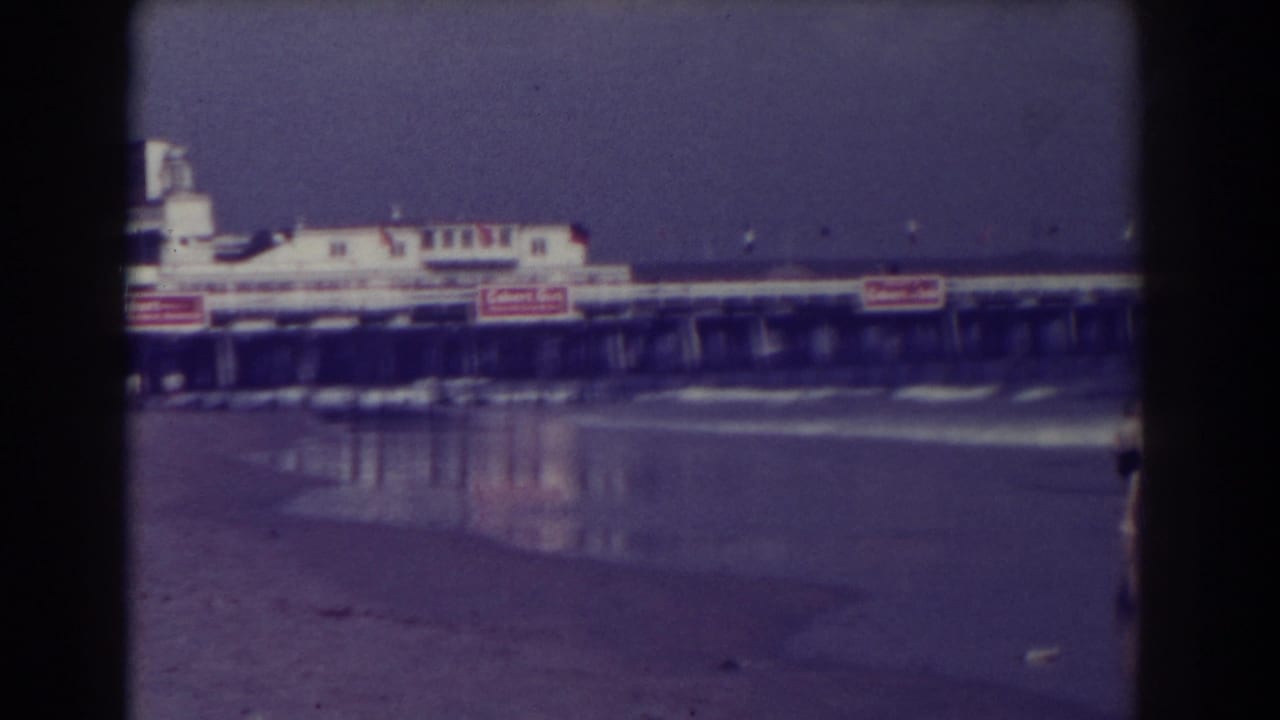 Atlantic City surf with a pier building and wet beach in the foreground.