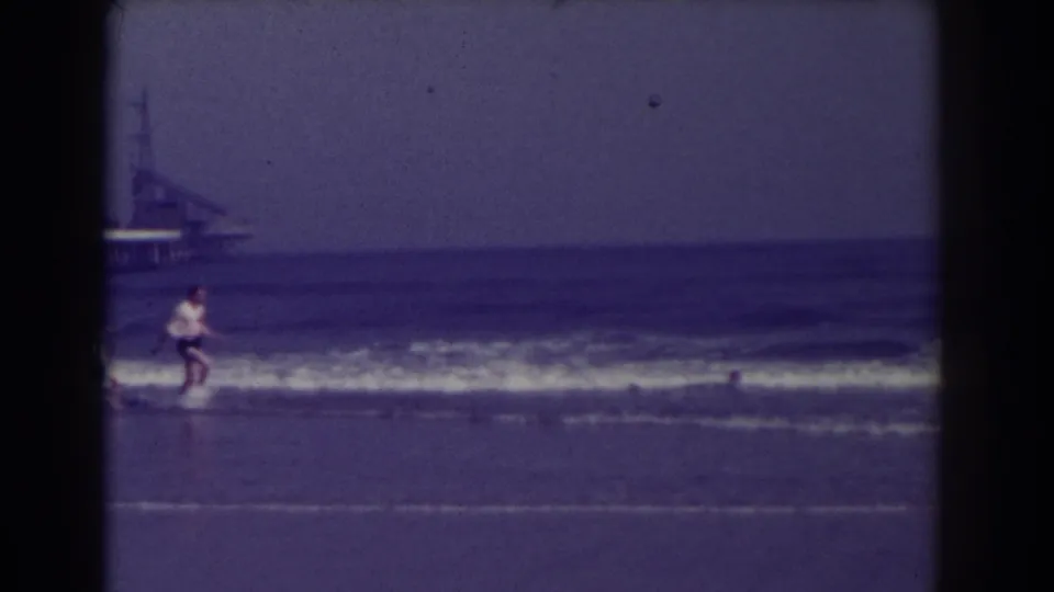 A beachgoer runs along the Atlantic City shoreline in 1938, with waves and a distant pier structure behind them.