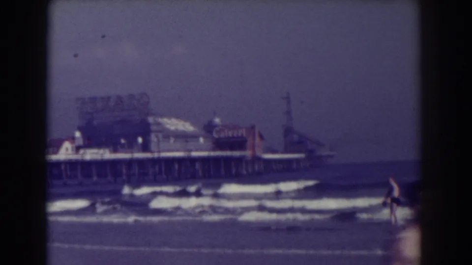 Atlantic City shoreline with waves, beachgoers, pier buildings, and a large Texaco sign visible in the 1938 home-movie frame.