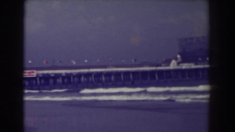 Atlantic City pier in 1938 with foamy waves below, a row of flags, and a red Texaco sign visible on the pier side.