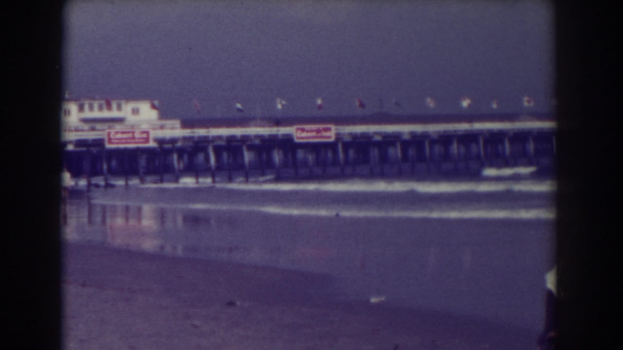Pier and shoreline with small watercraft near the surf and signage on the structure.