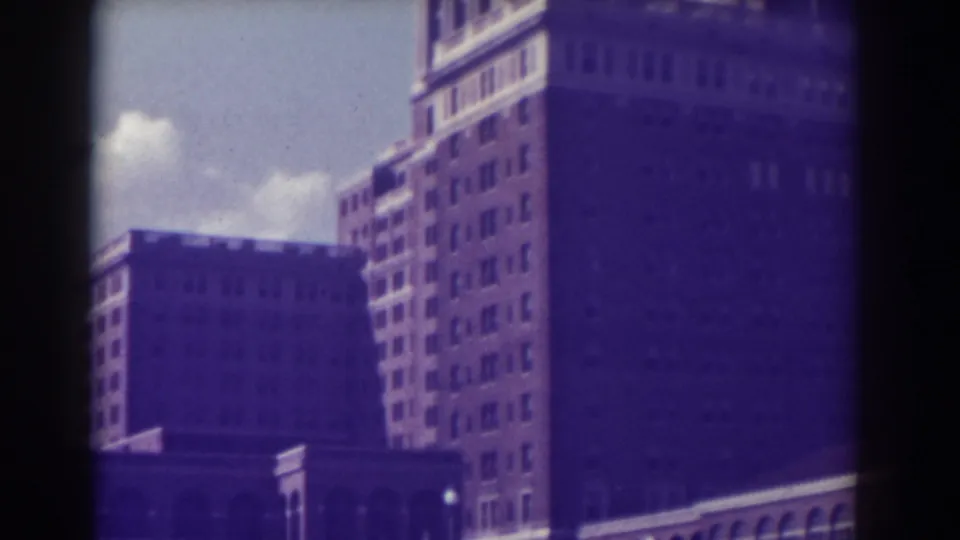 1938 Atlantic City 8mm frame showing the upper floors of a tan-brown multistory building against blue sky.