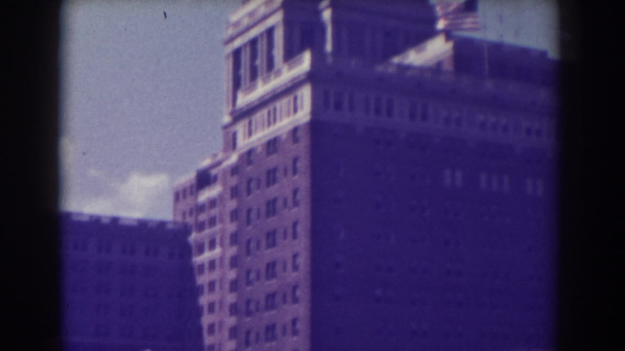 Tall building facade and rooftop area with a small American flag visible.