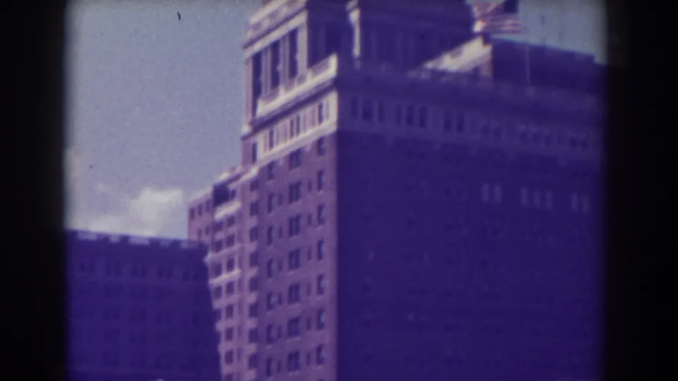 1938 Atlantic City 8mm frame with a tall building, rooftop structure, and small American flag near the roofline.