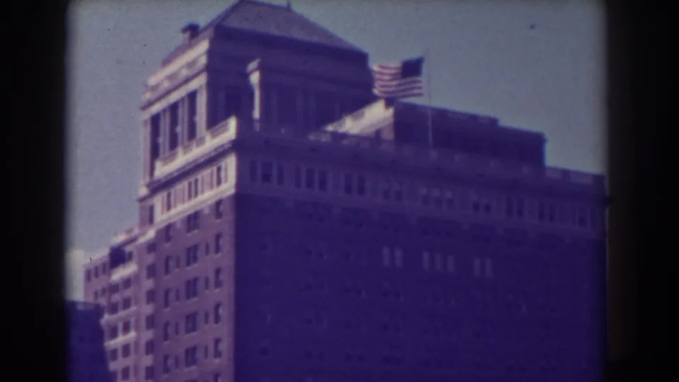 1938 Atlantic City 8mm frame focusing on the roofline of a large building with an American flag above it.