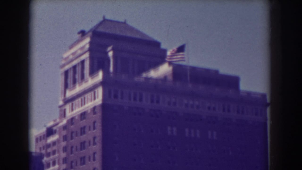 Tall building with American flag against a bright sky, seen through dark film edges.