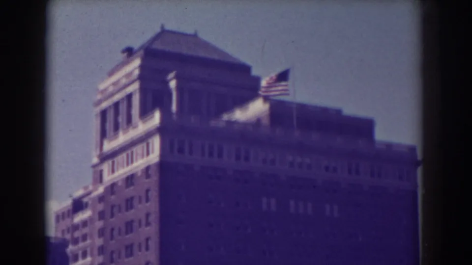 1938 Atlantic City home-movie frame showing a tall masonry building with rows of windows and an American flag near the roofline.