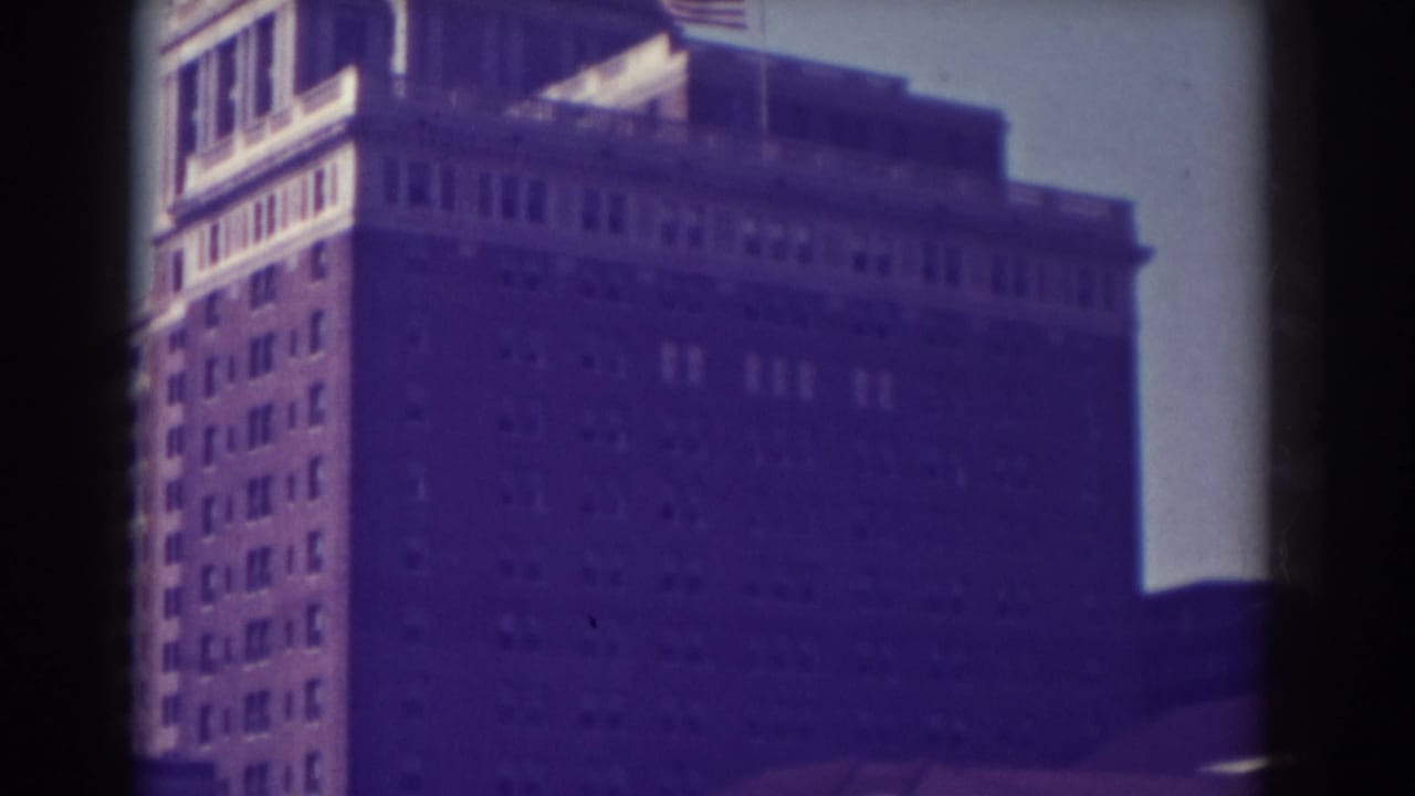 Upper stories of a large building with a flag near the roof, framed by film borders.