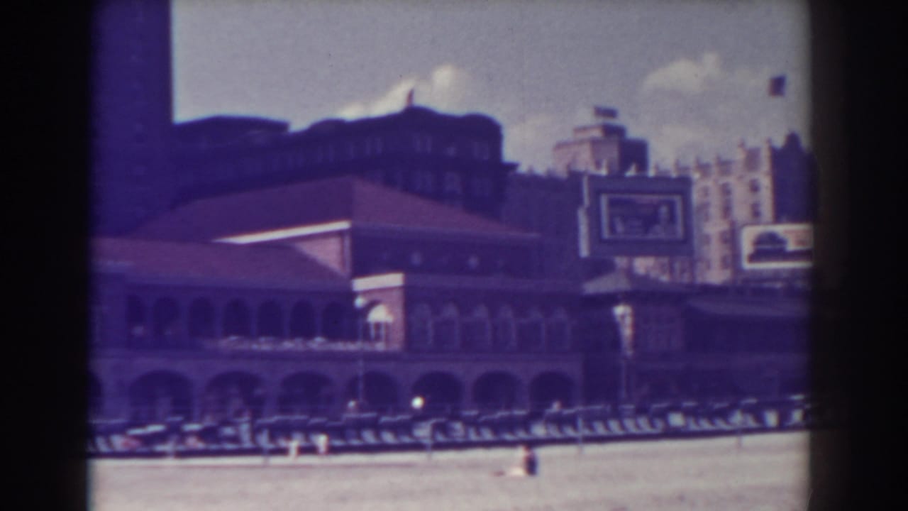Boardwalk building and tall background structures viewed across the beach.